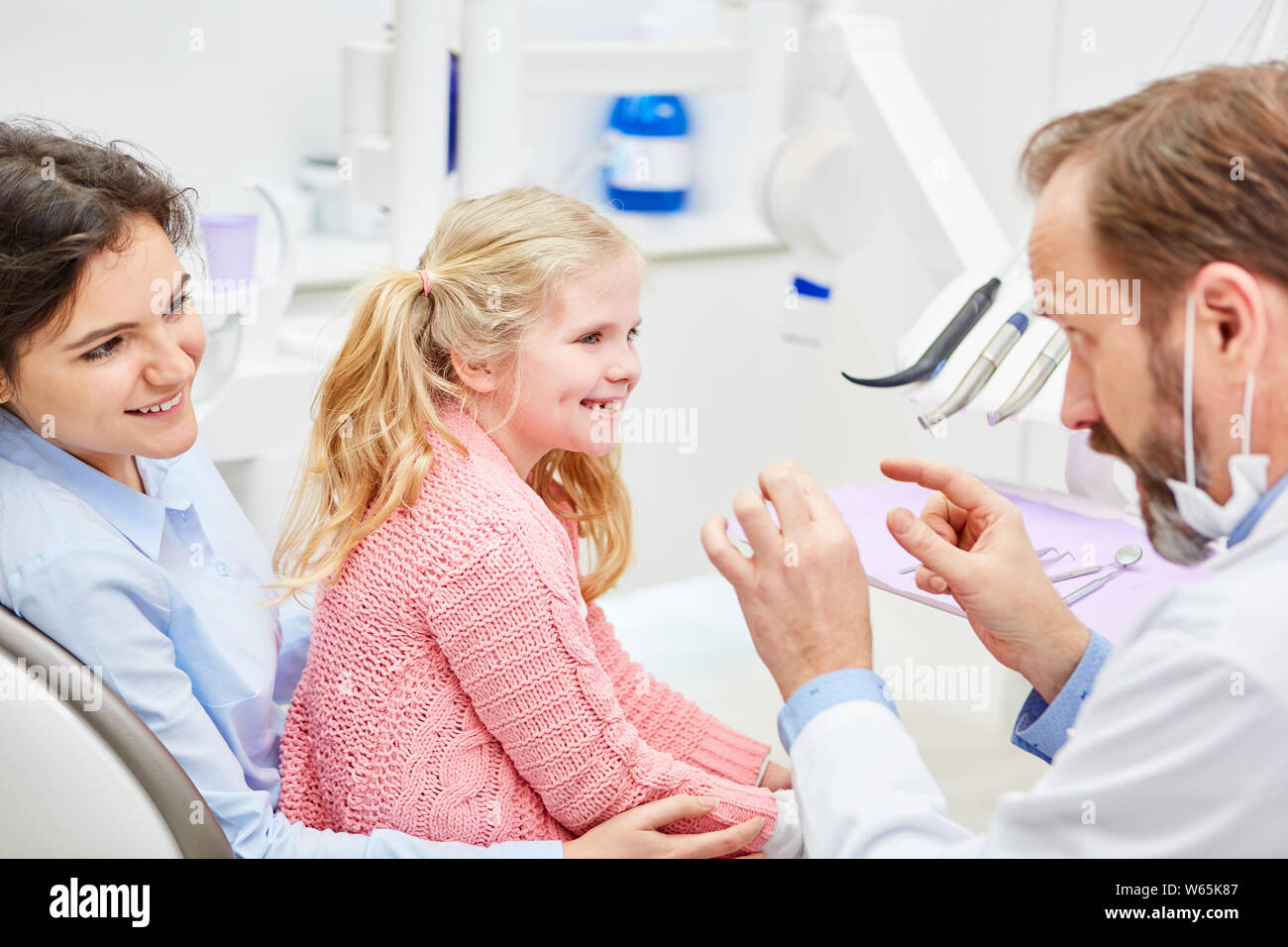 Pediatric dentist explains the mother and child the treatment in the consultation in the doctor's office Stock Photo