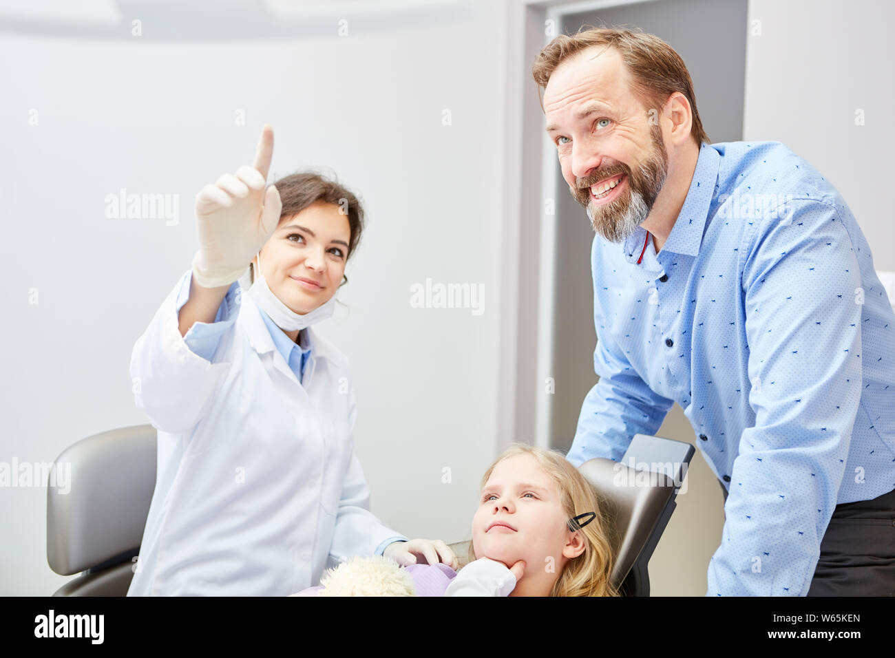 Pediatric dentist and physician assistant explain child's treatment to the screening examination Stock Photo