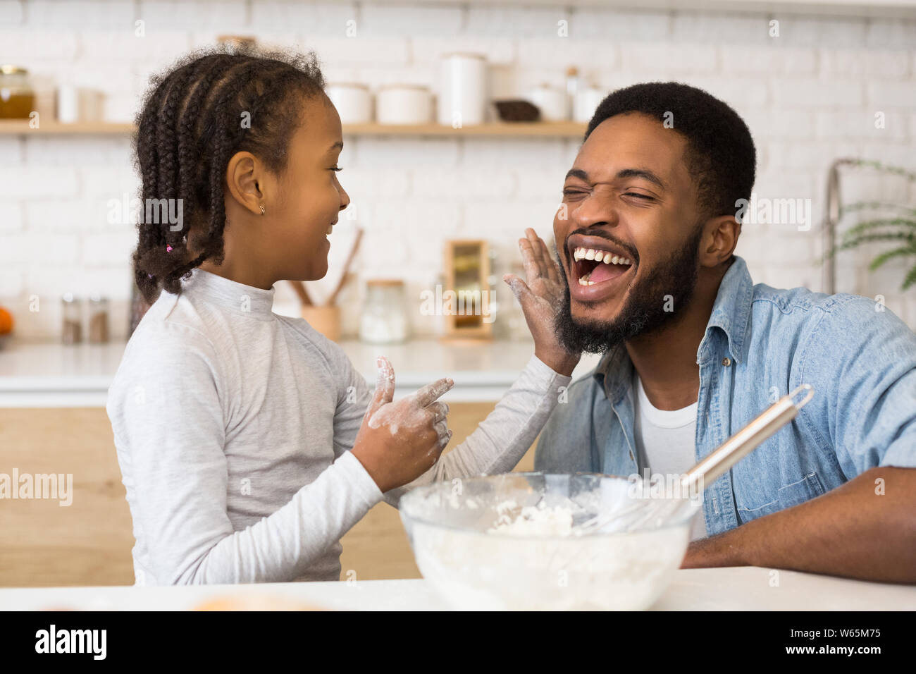 Little afro girl and her dad enjoying making pastry Stock Photo