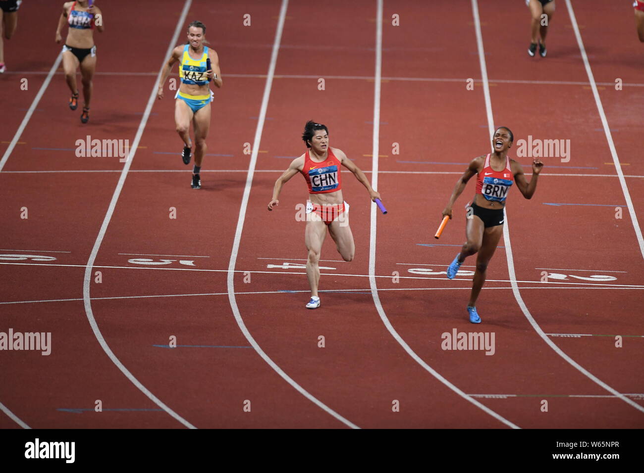 Salwa Naser of Bahrain, right, crosses the finish line to win in the women's 4x100m relay final of the athletics competition during the 2018 Asian Gam Stock Photo