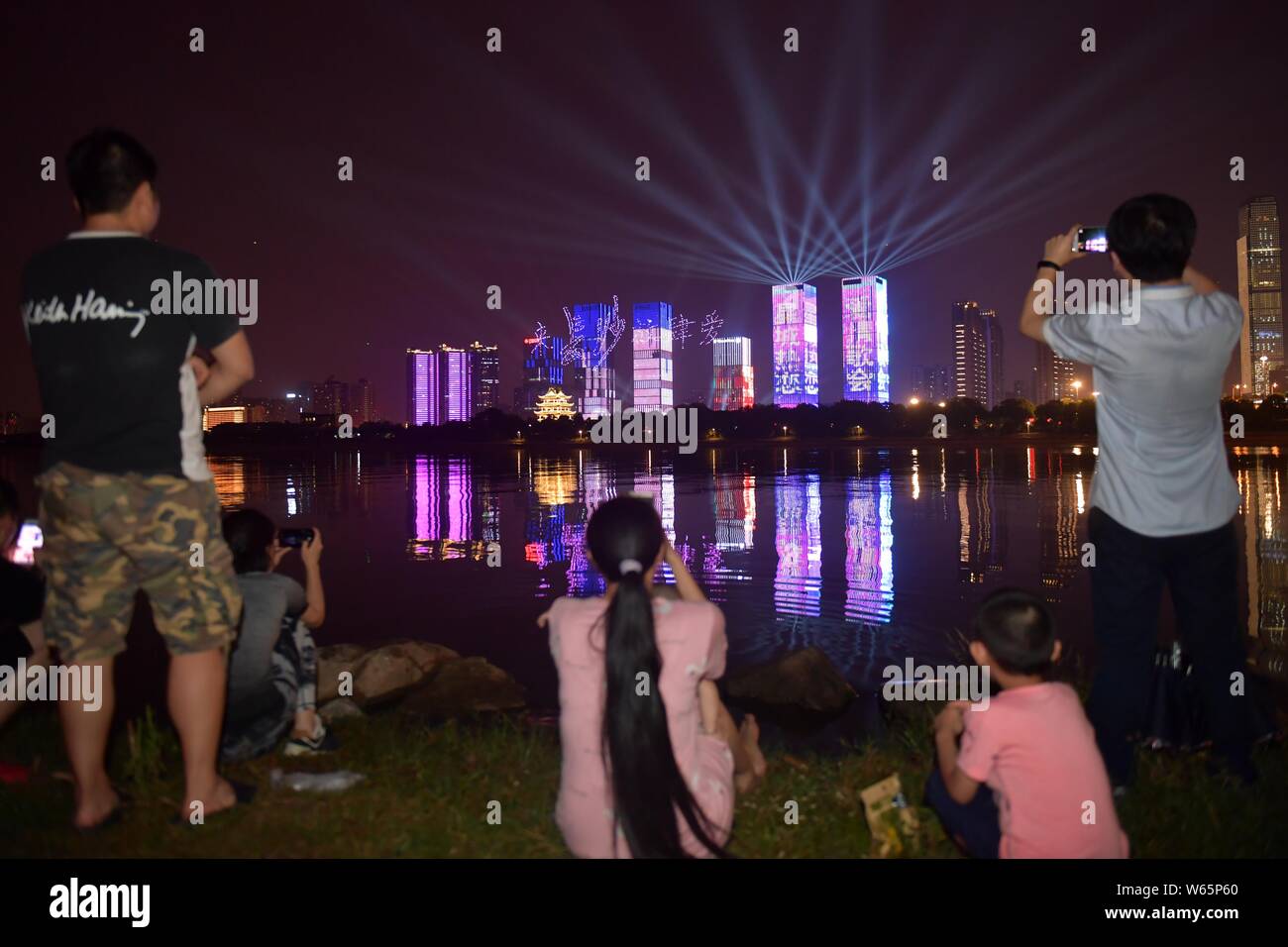 Local residents watch 777 drones or UAVs (unmanned aerial vehicles) forming patterns and words that represent 'love' to light up the sky as part of ce Stock Photo