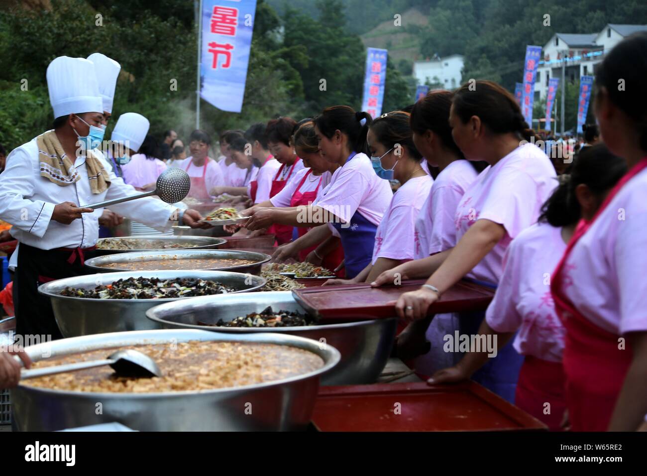 Chefs and waitresses serve tourists during a free-flowing banquet held at the parking lot of the Laojun Mountain scenic spot in Qiliping village, Luan Stock Photo
