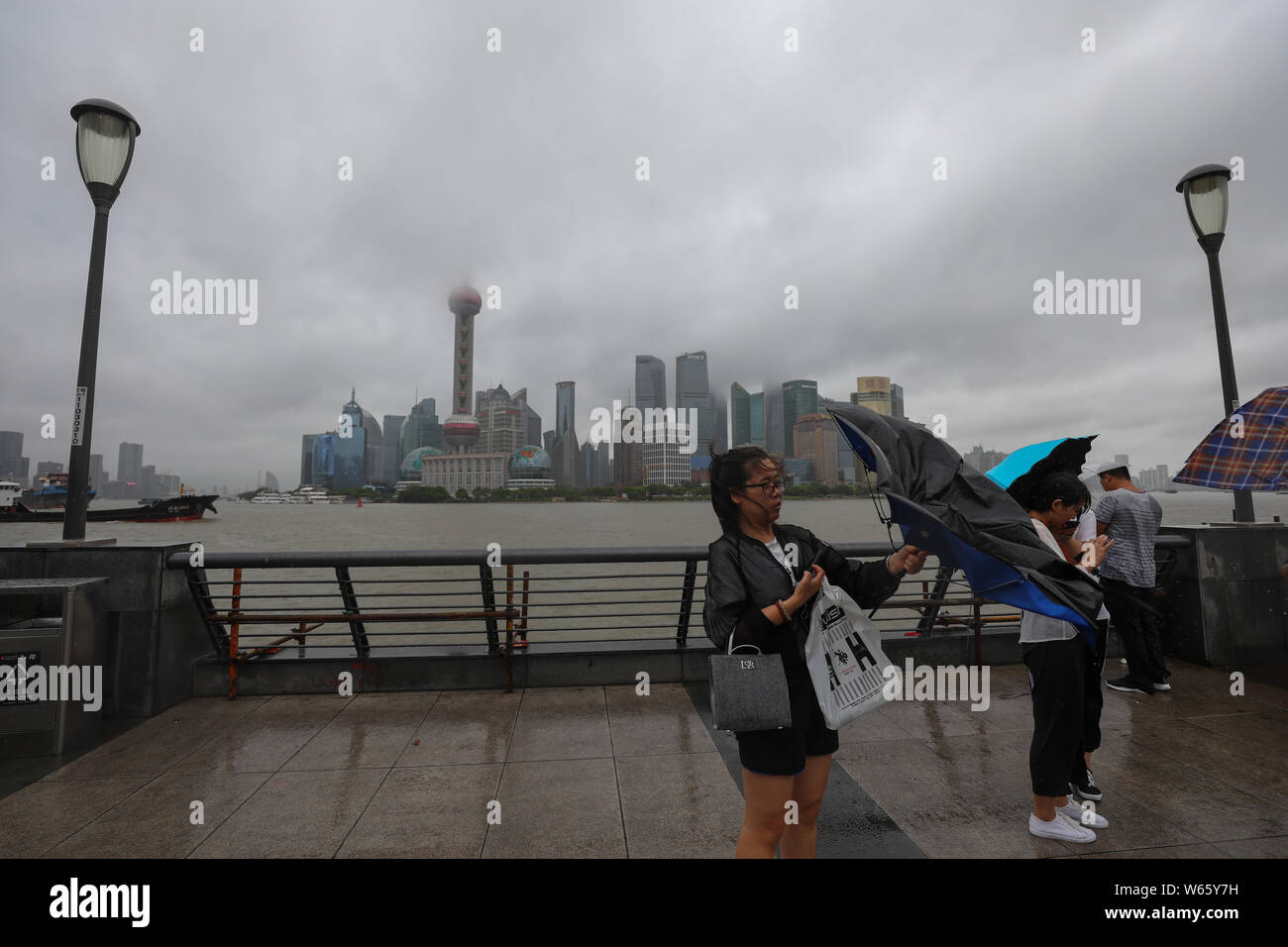 Tourists shield themselves with umbrellas as they brave strong wind and