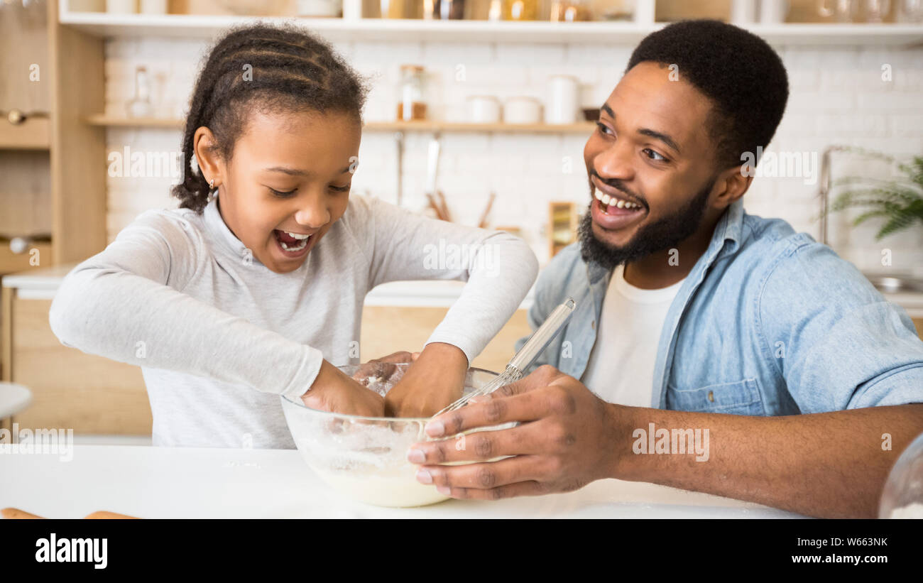 Excited afro girl playing with dough in kitchen Stock Photo