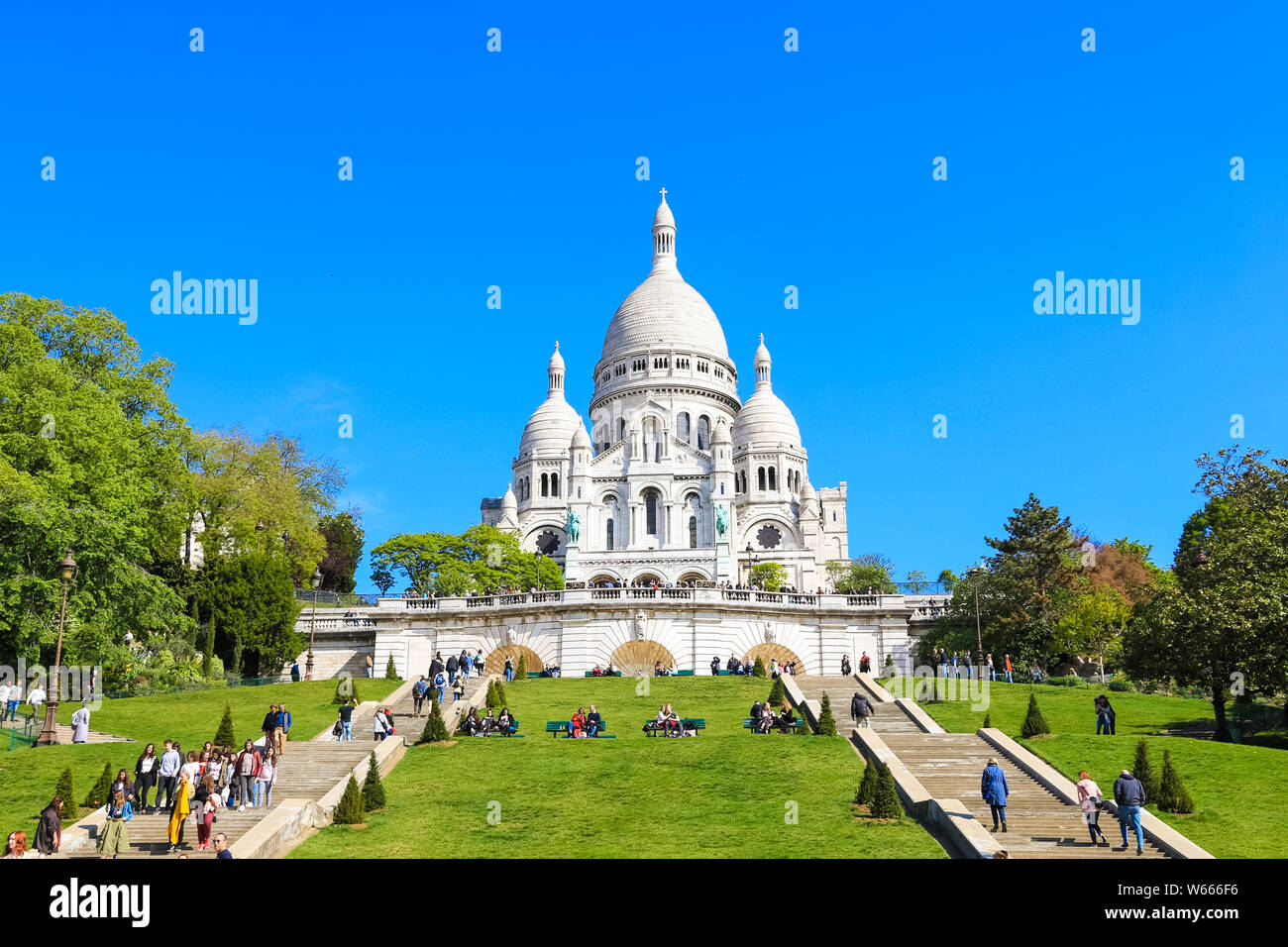 Lovely view of the famous Basilica of Sacré-Cœur with its white facade seen from the base of the butte Montmartre in Paris. It is a popular landmark... Stock Photo