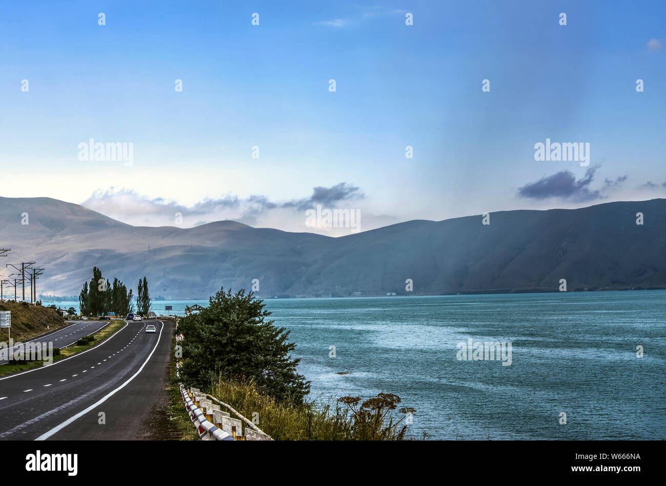 A sharp turn on the road along the coast of the high-mountain lake Sevan, surrounded by the mountains of the Gegham range Stock Photo