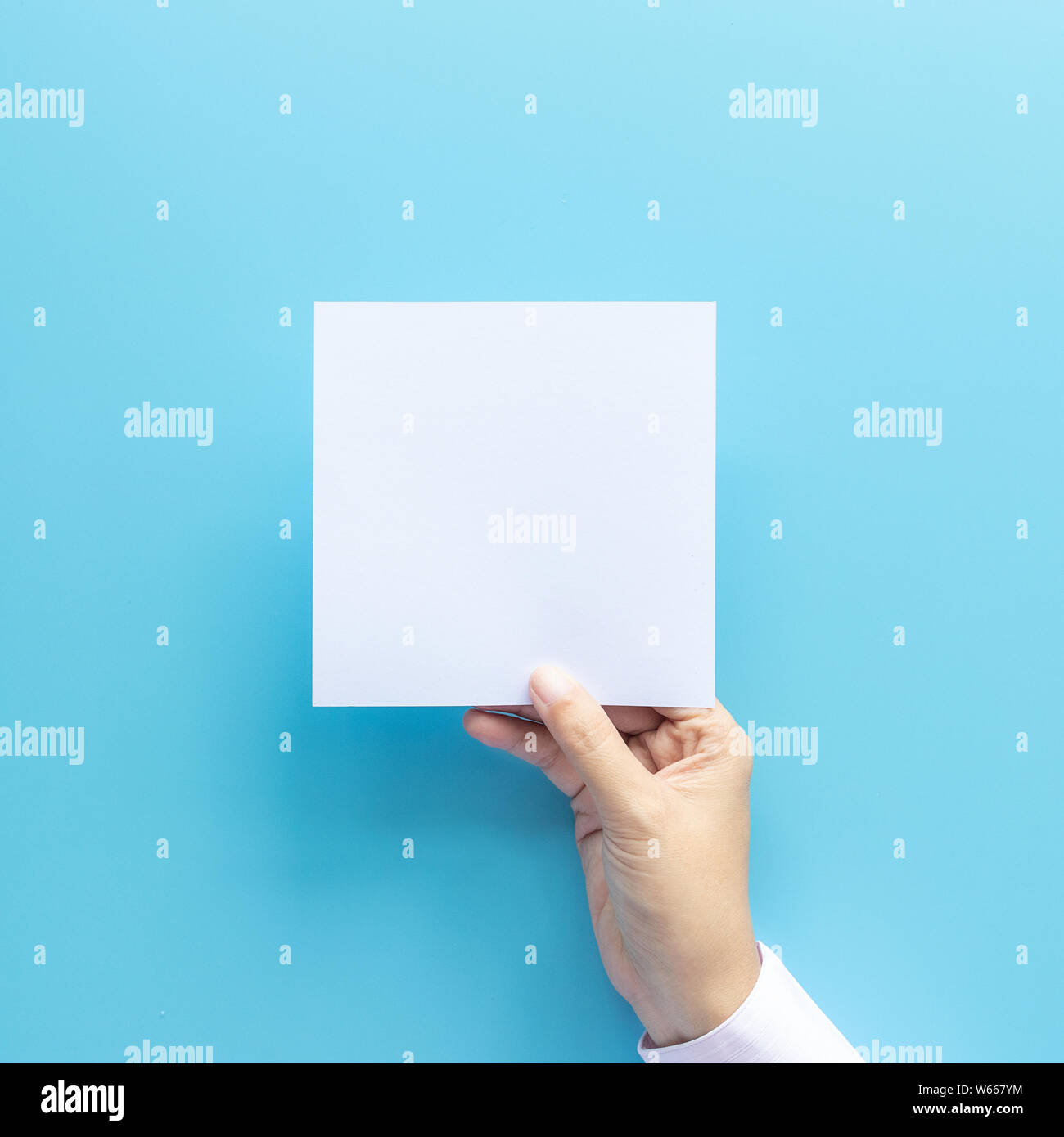 woman hand holding blank paper sheet isolated on blue background with copy space. Stock Photo