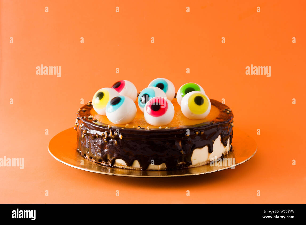 Halloween cake with candy eyes decoration on orange background ...