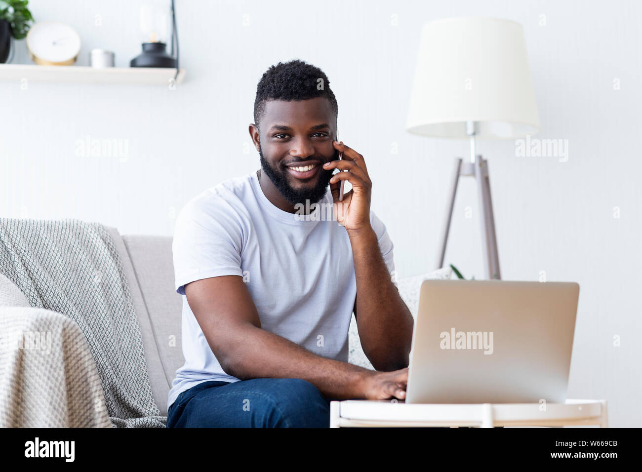 Black man working on laptop and calling Stock Photo