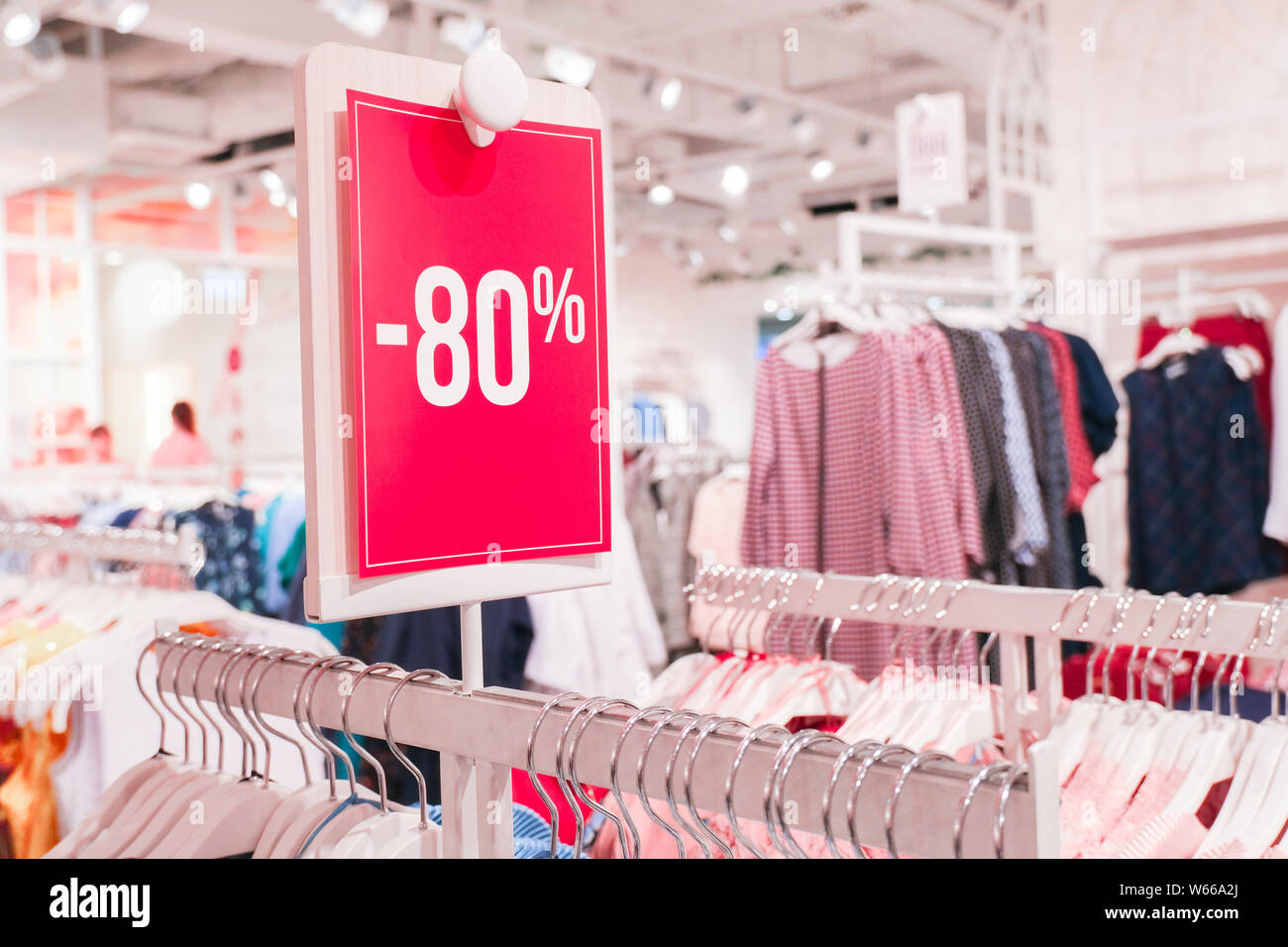 Season sale, black friday and shopping concept. Red label 80 percent discount price in shop. Clothes hangers on background. Stock Photo