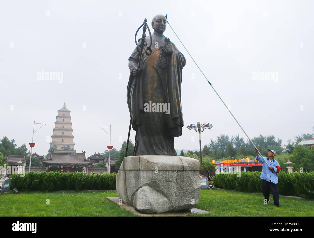 A Chinese worker cleans a bronze statue of Chinese Buddhist monk