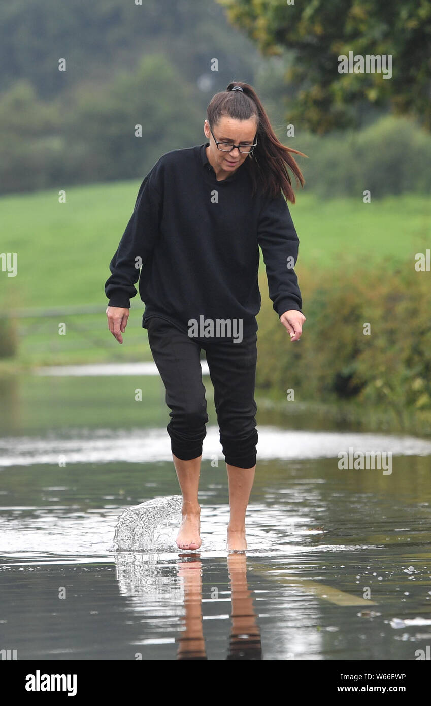 A woman makes its way along the flooded Bonis Hall Lane, Cheshire