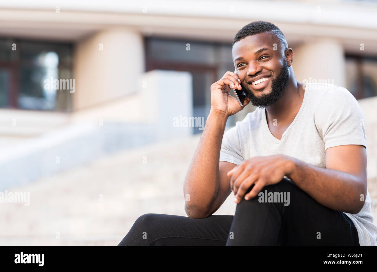 Shy african guy with white smile talking on phone with happiness Stock Photo