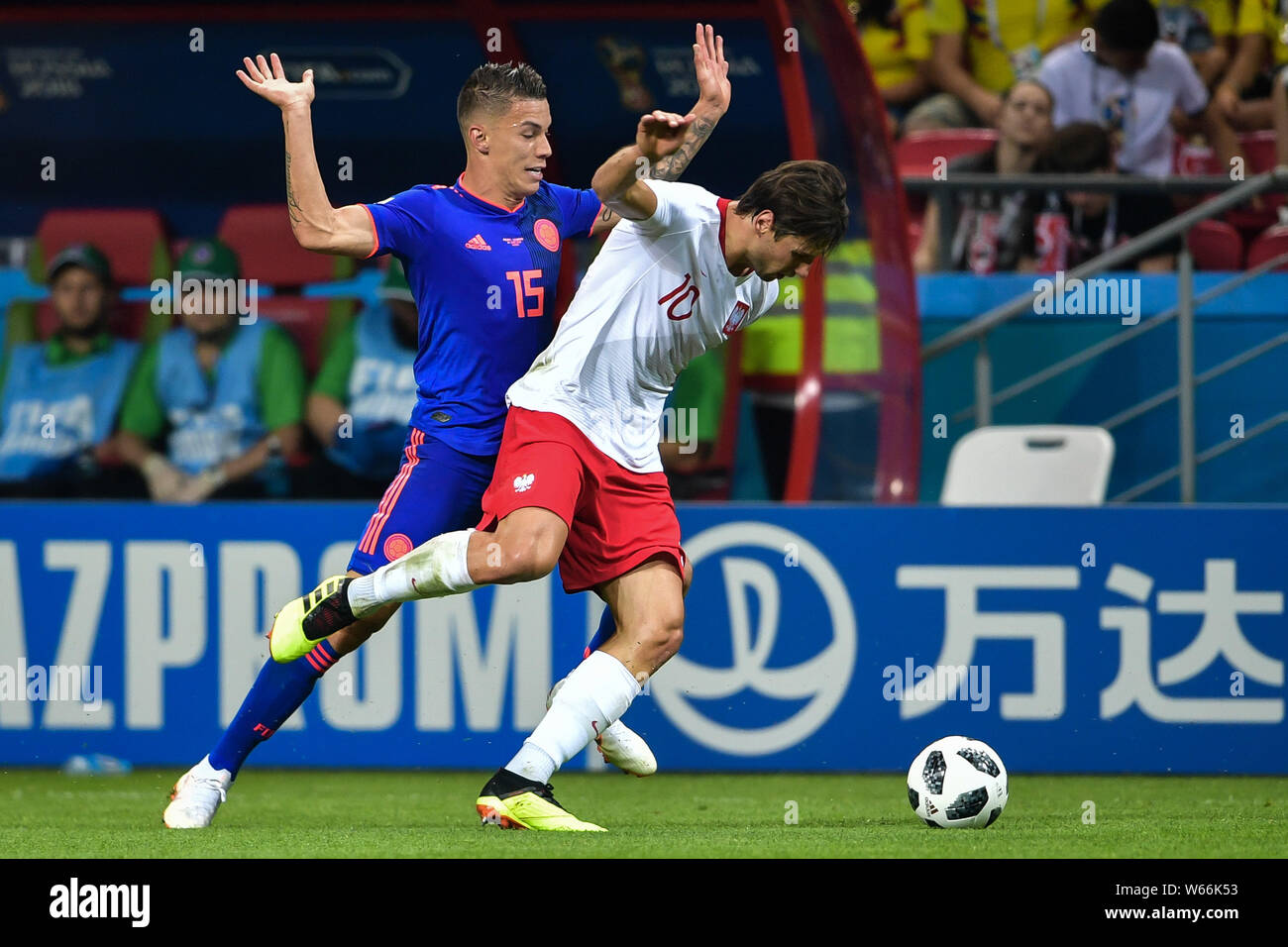 Mateus Uribe of Colombia, left, challenges Grzegorz Krychowiak of Poland with an advertising board for Chinese conglomerate Dalian Wanda Group in the Stock Photo