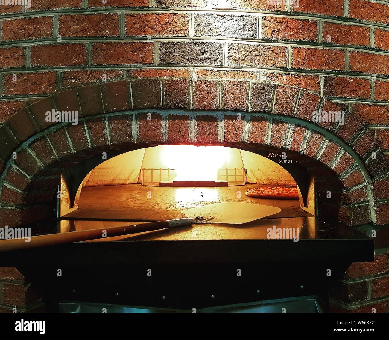 Pizza in a brick oven and peel. Stock Photo