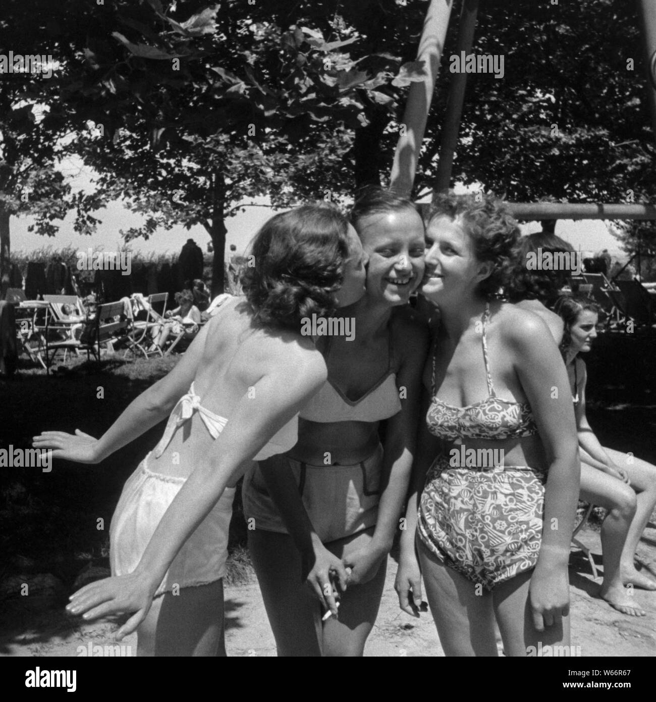 three young hungarian girls wearing vintage swimsuits two of them kissing the third on the cheek at a holiday resort 1950s hungary Stock Photo