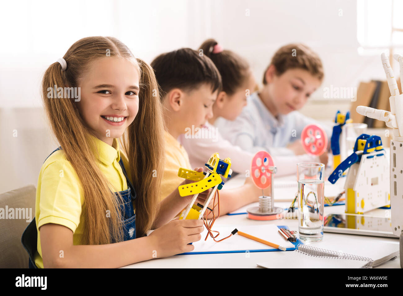 Adorable schoolgirl holding robot model at STEM classroom Stock Photo