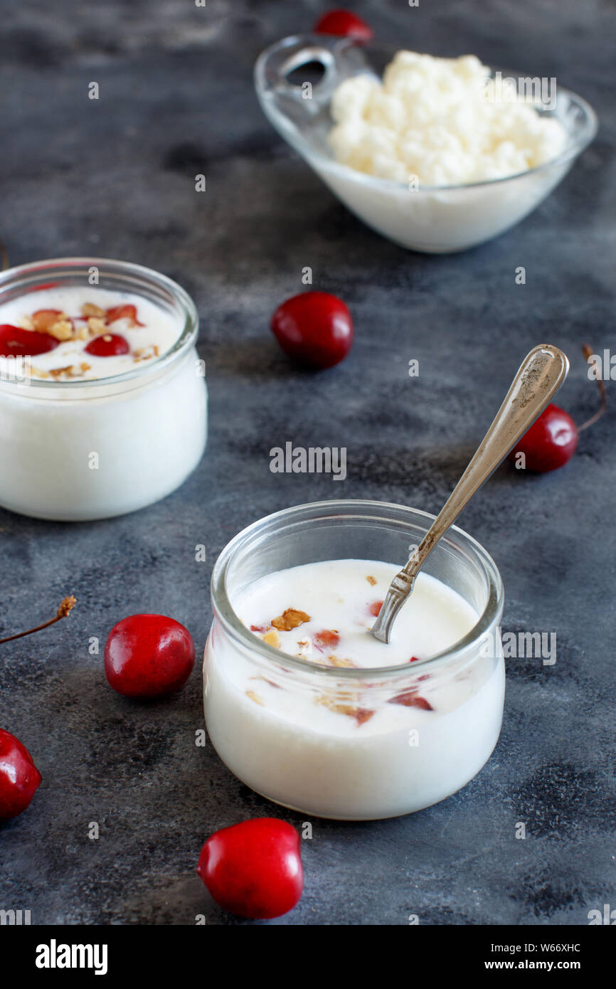 Fermented yogurt kefir in small bottles with cherries and walnuts close up Stock Photo