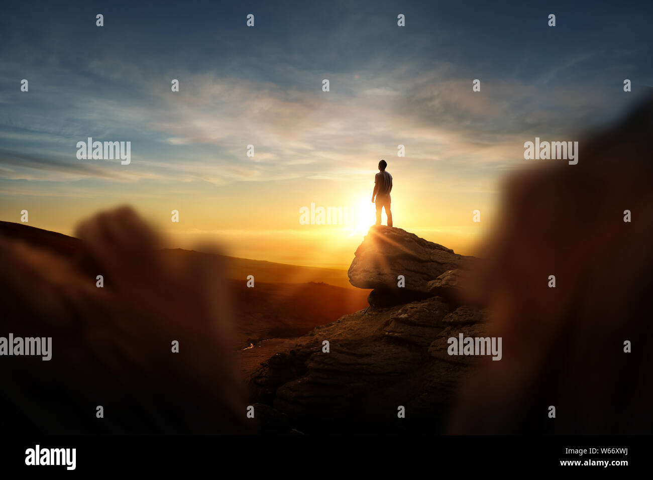 Leadership And Goals. A man standning on top of a mountain watching the sun set. Conceptual photo composite. Stock Photo