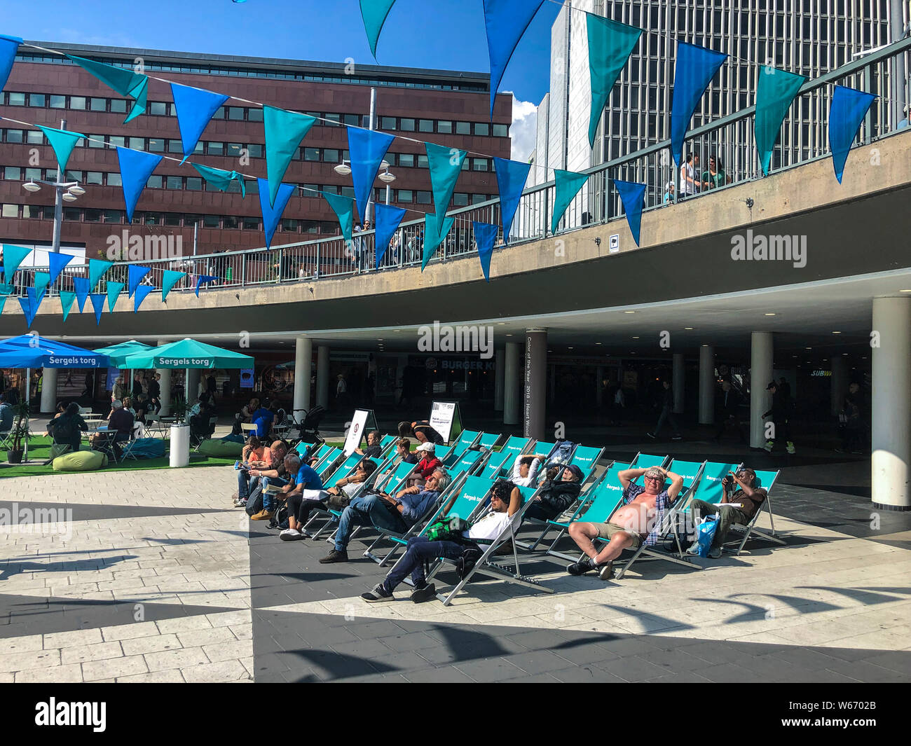 Summer in central Stockholm with deck-chairs for sun-bathers on Sergels Torg in the center of the city Stock Photo