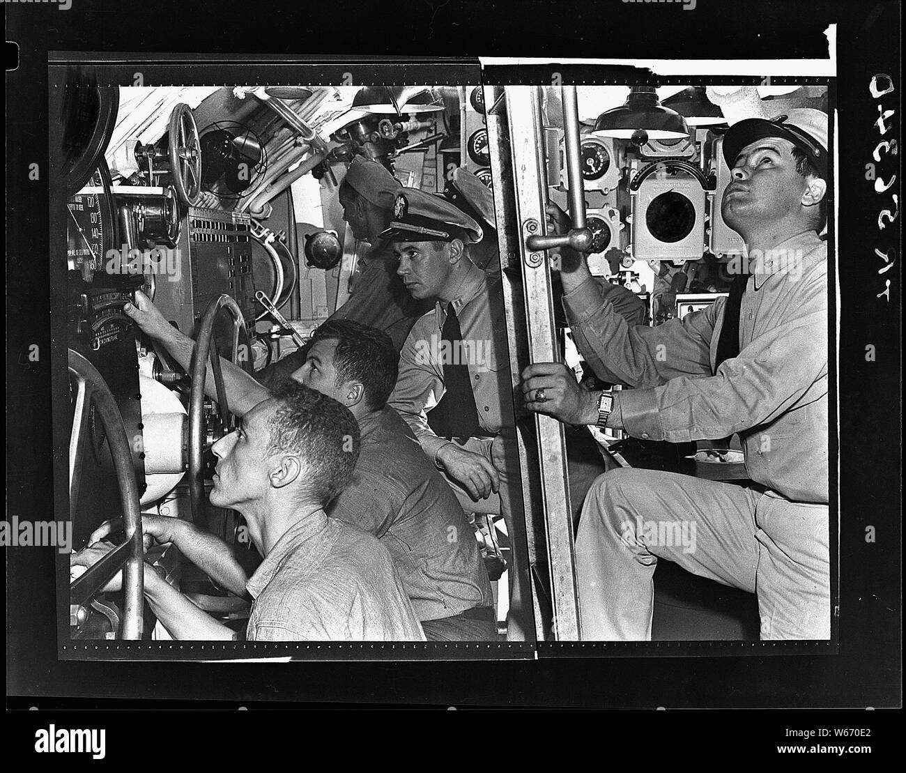 Lcdr. John R. Madison prepares to go up ladder from control room of USS Muskallunge (SS 262) at submarine base New London, Connecticut. Lt. William B. Robb is at his station. Stock Photo