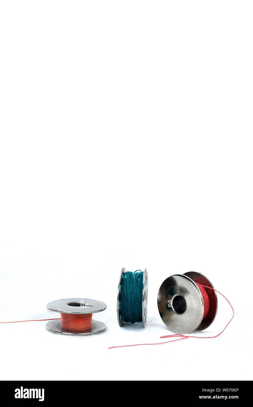 metal spool of colored threads on white background with reflection
