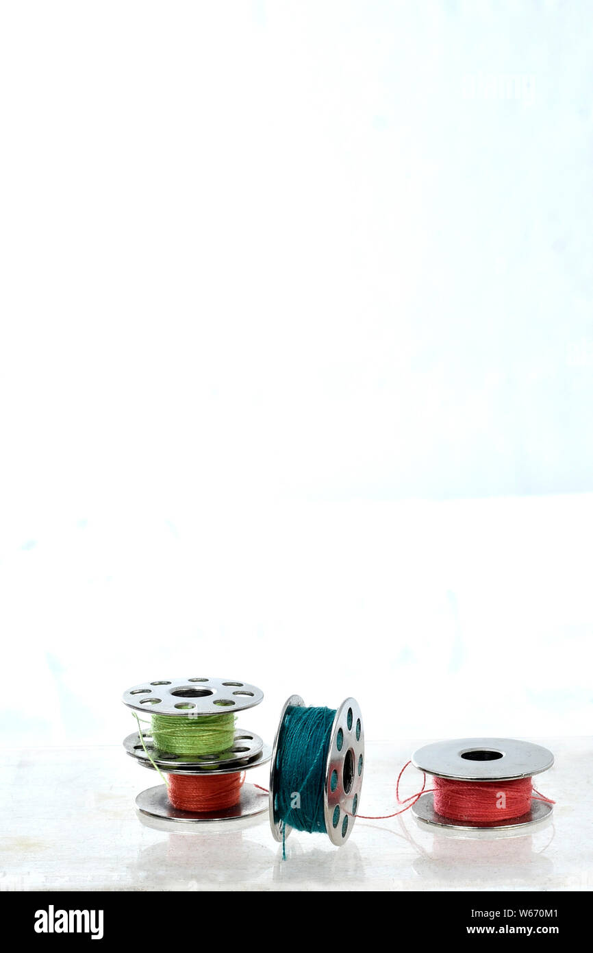 metal spool of colored threads on white background with reflection