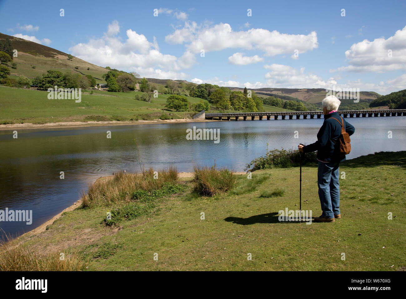 Woman walker enjoying view of Ladybower Reservoir, the largest (holding 6300 million gallons) of three water storage reservoirs in the Derwent Valley, Stock Photo