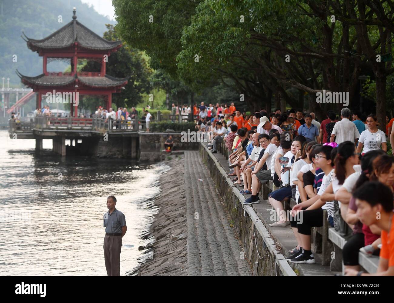 Tourists sit along the Xinanjiang River, where the water temperature remains at around 17 degrees Celcius, at a scenic spot in Jiande city, Hangzhou c Stock Photo