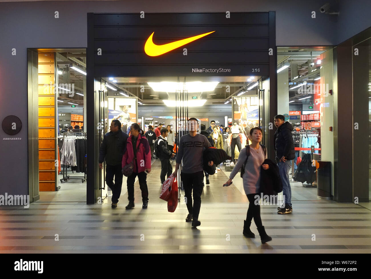FILE--Pedestrians walk past a Nike store in Shanghai, China, 2 July 2018.  Nike Inc said on Monday it would raise wages for about 7,500 employees f  Stock Photo - Alamy