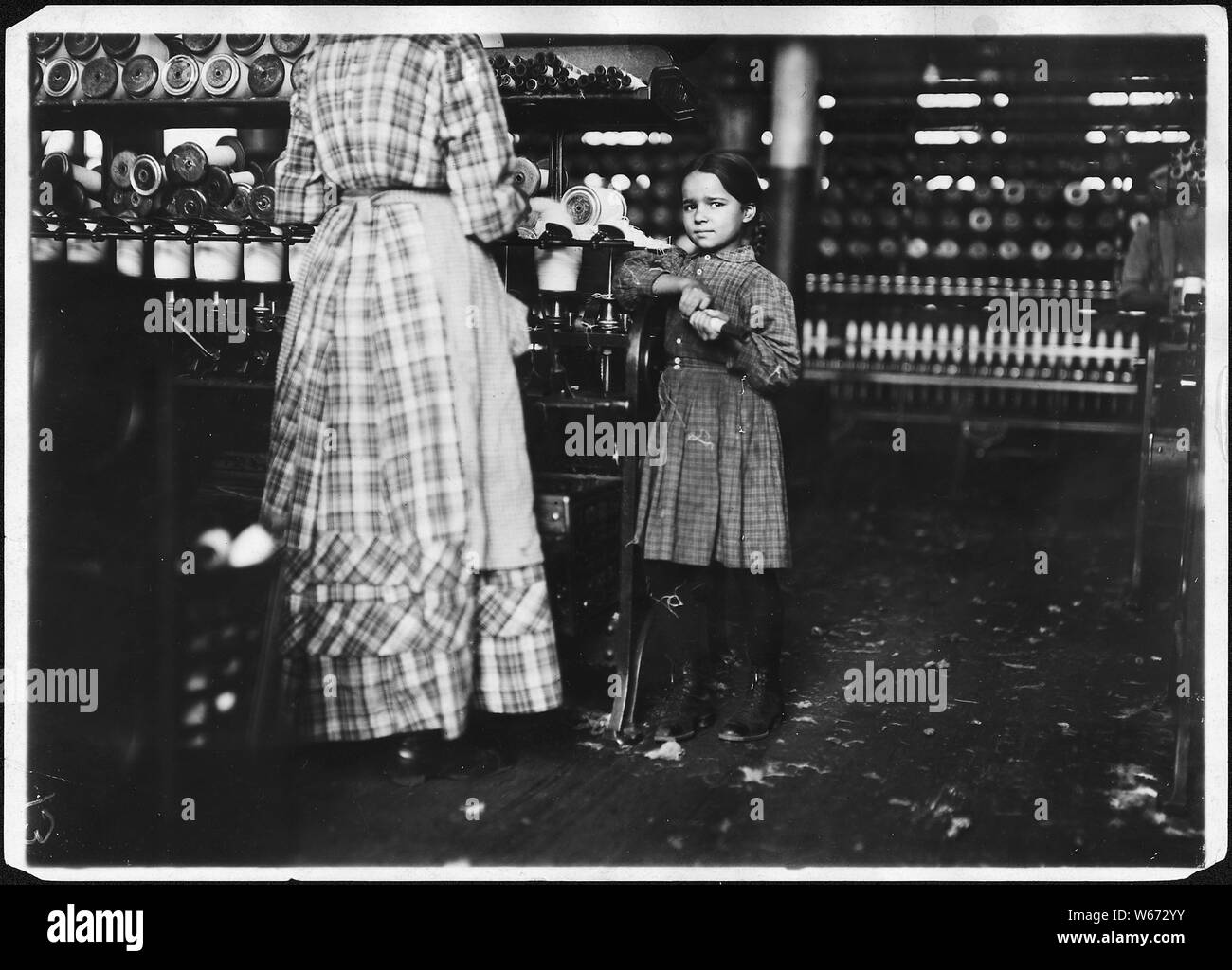 Little Fannie, 7 years old, 48 inches high, helps sister in Elk Cotton Mill. Her sister said, Yes she helps me right smart. Not all day but all she can. Yes she started with me at 6 this mornin'. These two belong to a family of 19 children. Fayetteville, Tenn. Stock Photo