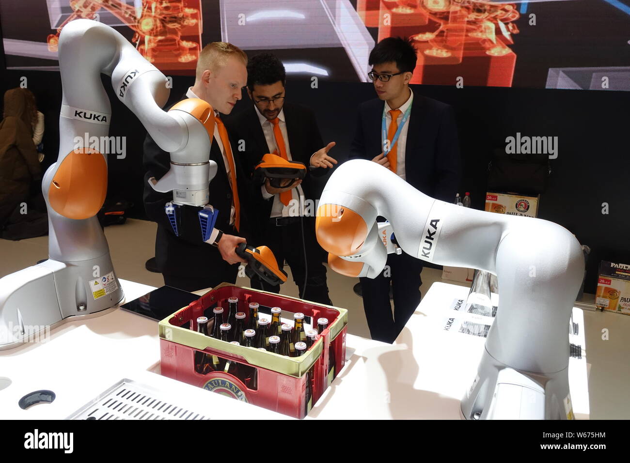 --FILE--Visitors look at a robot arm of German robot maker Kuka during an exhibition in Shanghai, China, 10 March 2018.   German robot maker Kuka is e Stock Photo