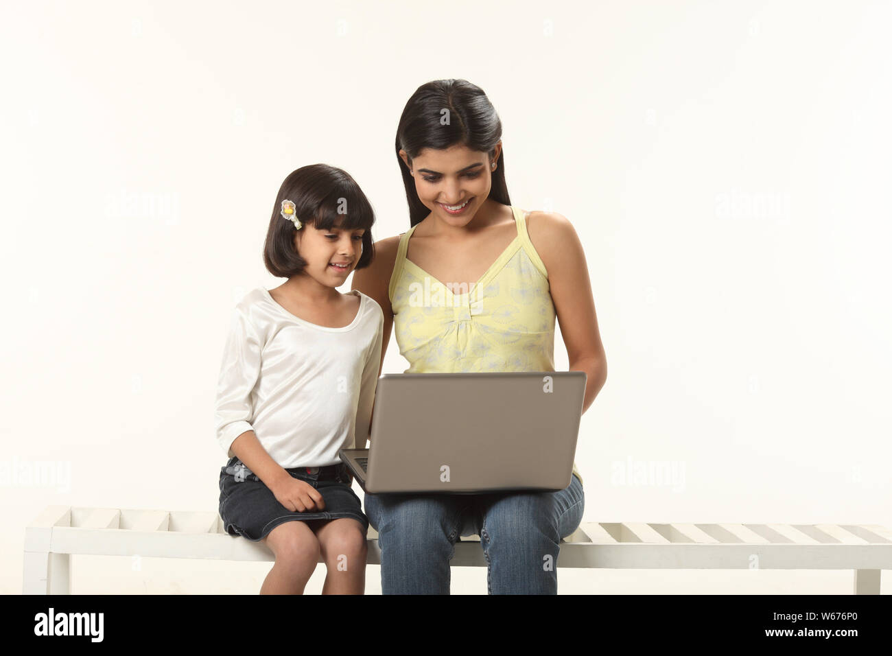 Woman using a laptop with her daughter Stock Photo