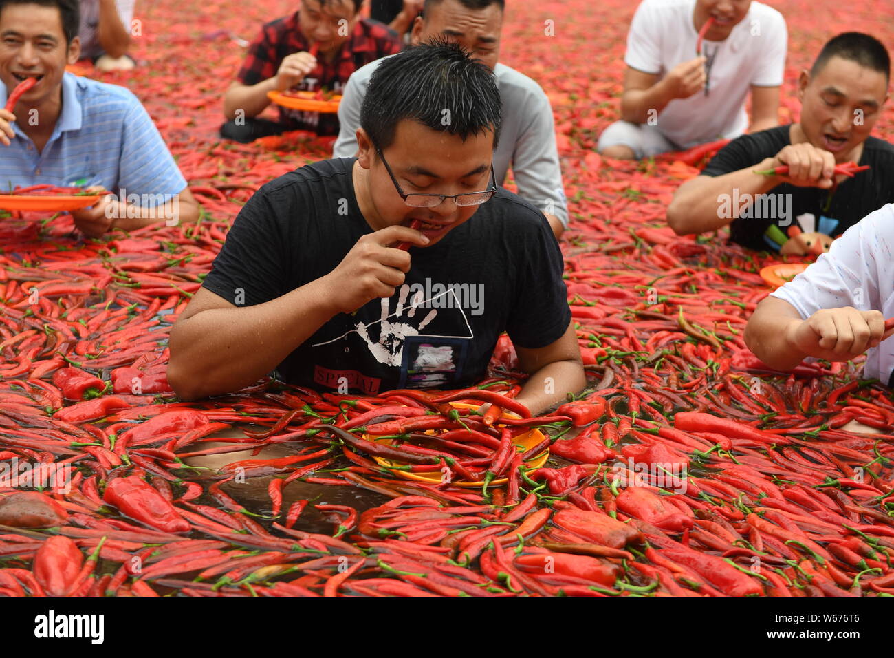 A participant sitting in a big pool filled with chili takes part in an