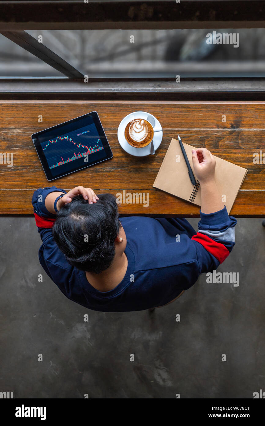 Business analyst grabbing her head while watching stock trading graph Stock Photo