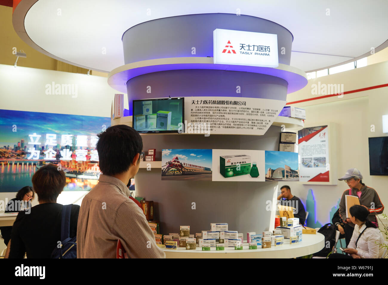 --FILE--People visit the stand of Tasly Pharmaceutical Group during an exhibition in Shanghai, China, 10 May 2014.   Tianjin-based Tasly Pharmaceutica Stock Photo