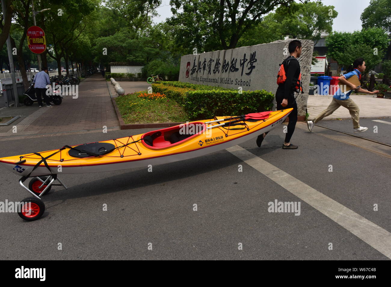 34-year-old Chinese gym teacher Sun Hua drags his boat after boating on a river as he arrives at school in Jiaxing city, east China's Zhejiang provinc Stock Photo