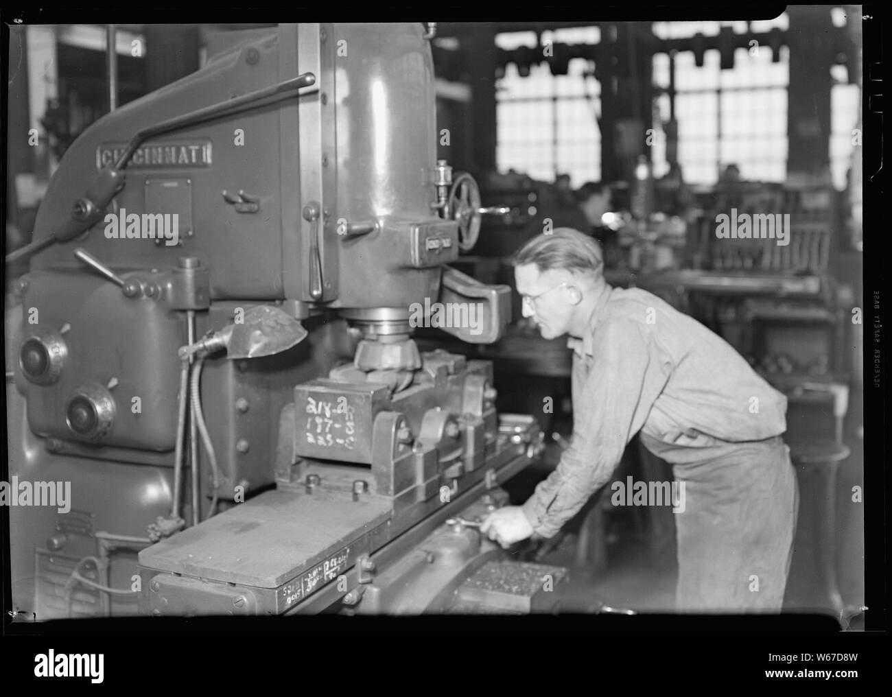Millville, New Jersey - Glass bottles. Mould shop Whitall Tatum Co. This skilled machinist is running a machine which faces off the mould and carves it to the shape of the bottle. Square iron blocks are hollowed out to the desired shape by this machine. Stock Photo
