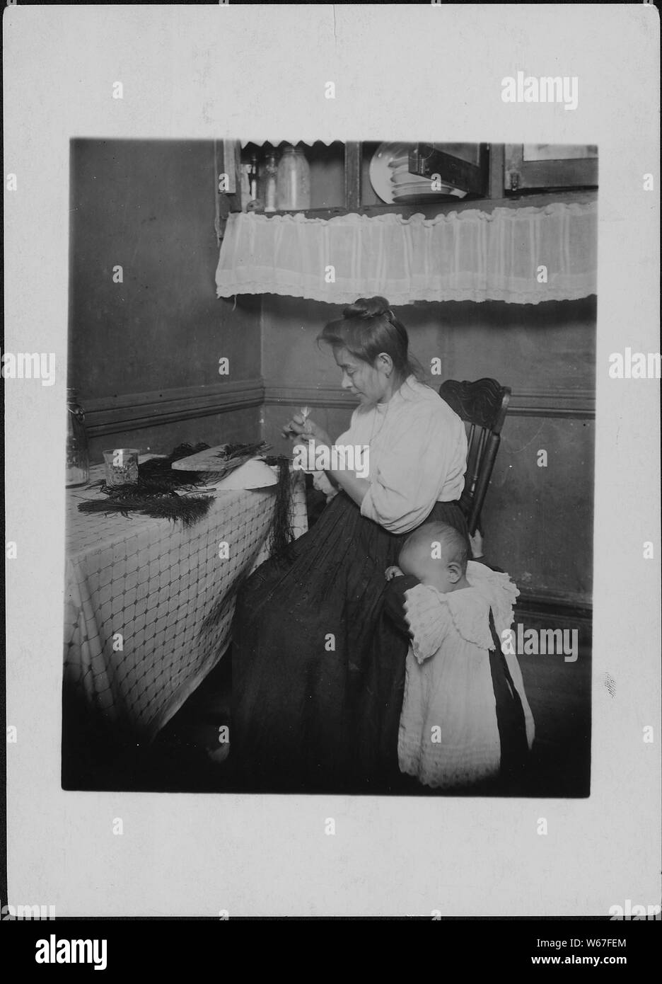 Mrs. Capello makes 50 [cents] to $1 a week making willow plumes. Husband works irregularly as a tailor. New York City. Stock Photo
