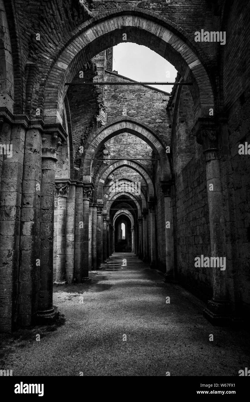 Vertical shot of a hallway with pillars and arched type doorways at Abbazia di San Galgano Stock Photo