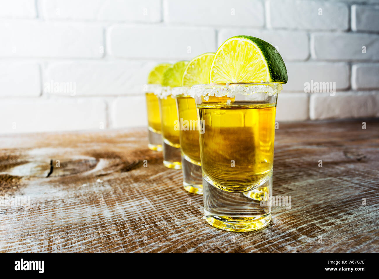 Gold Mexican tequila shots with lime slices on the rustic wooden ...