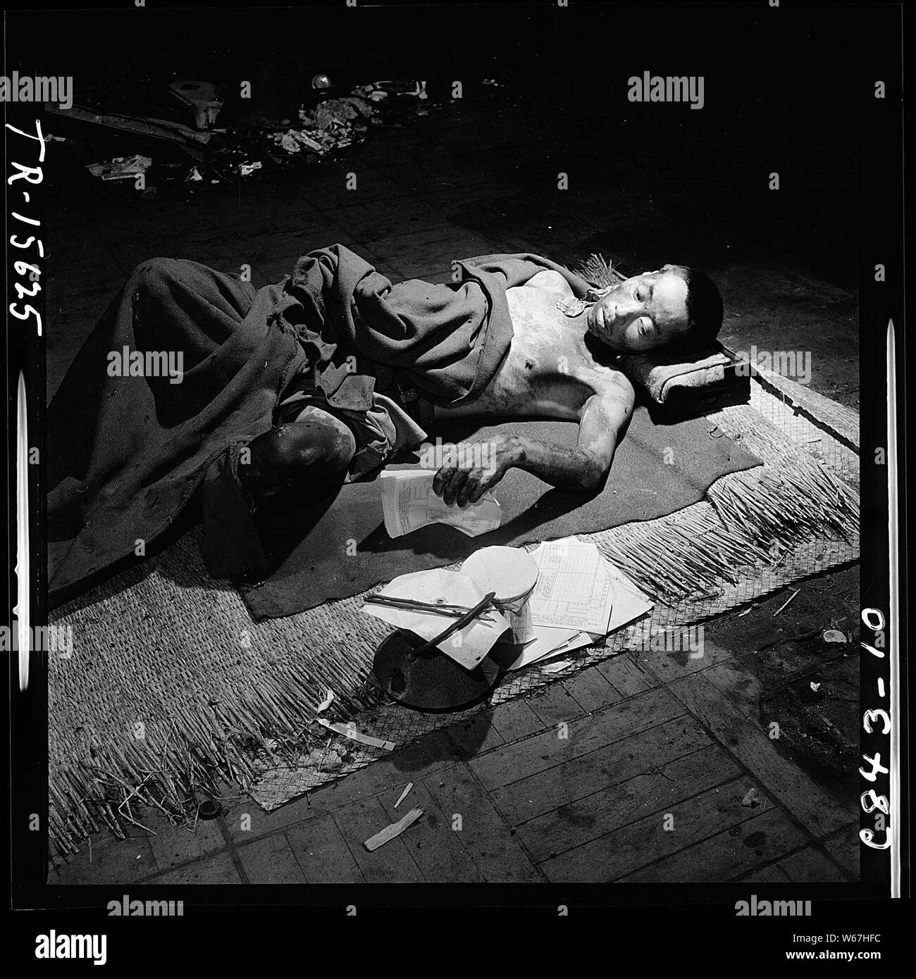 Navy photographer pictures suffering and ruins that resulted from atom bomb blast in Hiroshima, Japan. Victim lies in make-shift hospital in bank building. Stock Photo