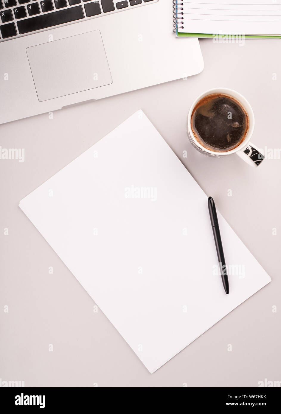 Top view of working table with blank paper notebook, cup of coffee