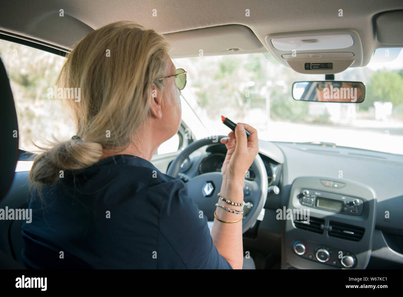 Frau schminkt sich während sie ein Fahrzeug steuert Stock Photo
