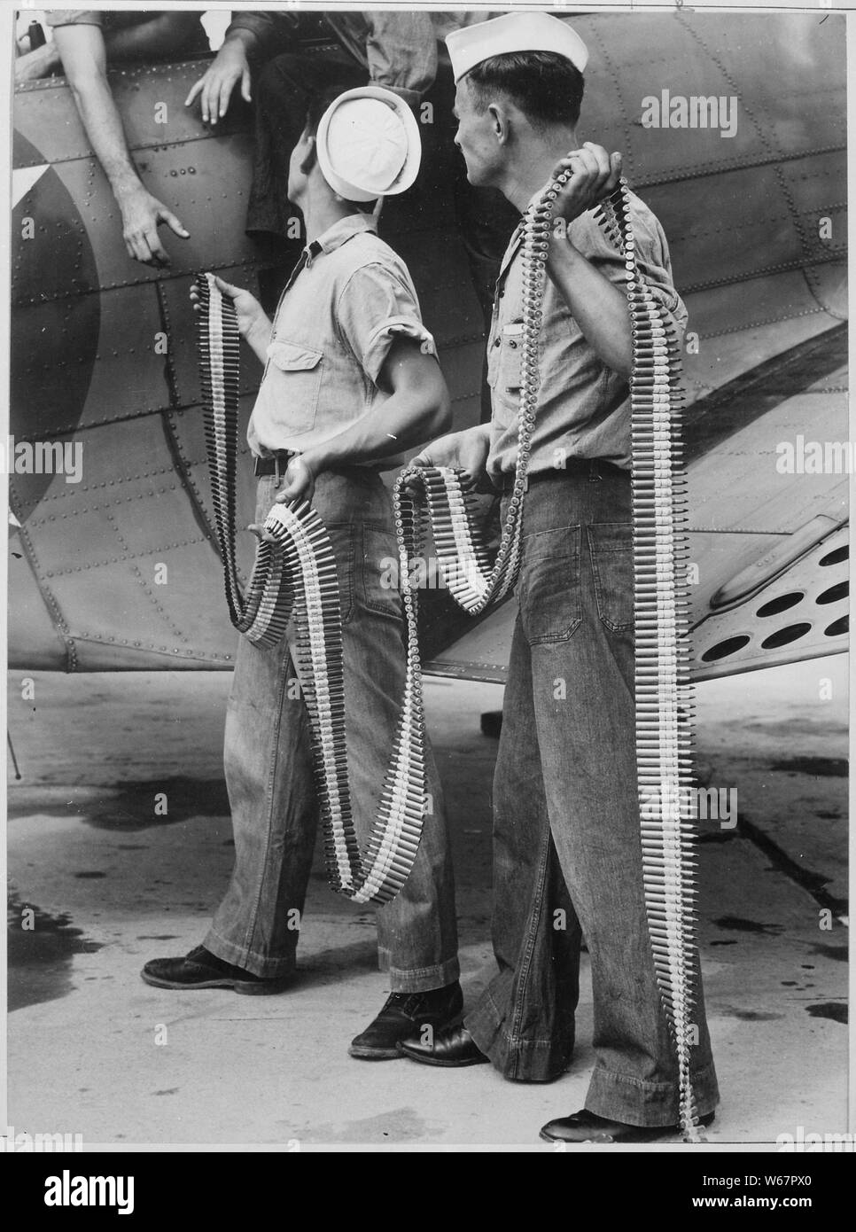 Ordnancemen loading belted cartridges into SBD-3 at Naval Air Station in Norfolk, Virginia; General notes:  Use War and Conflict Number 838 when ordering a reproduction or requesting information about this image. Stock Photo