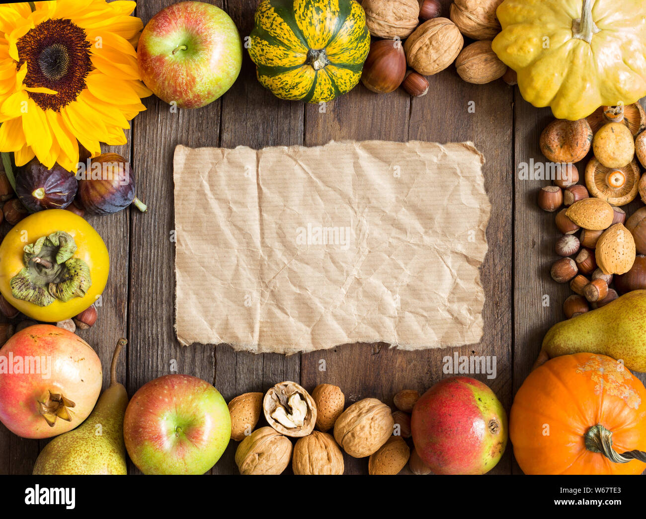 Autumn frame of fruits, vegetables, mushrooms, nuts and sunfloweron a wooden table Stock Photo