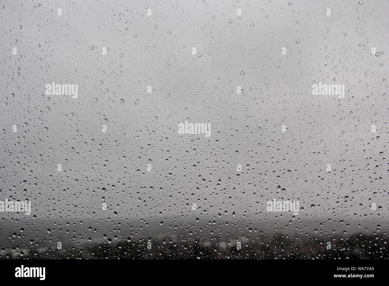 Raindrops on window-pane blurred background Stock Photo