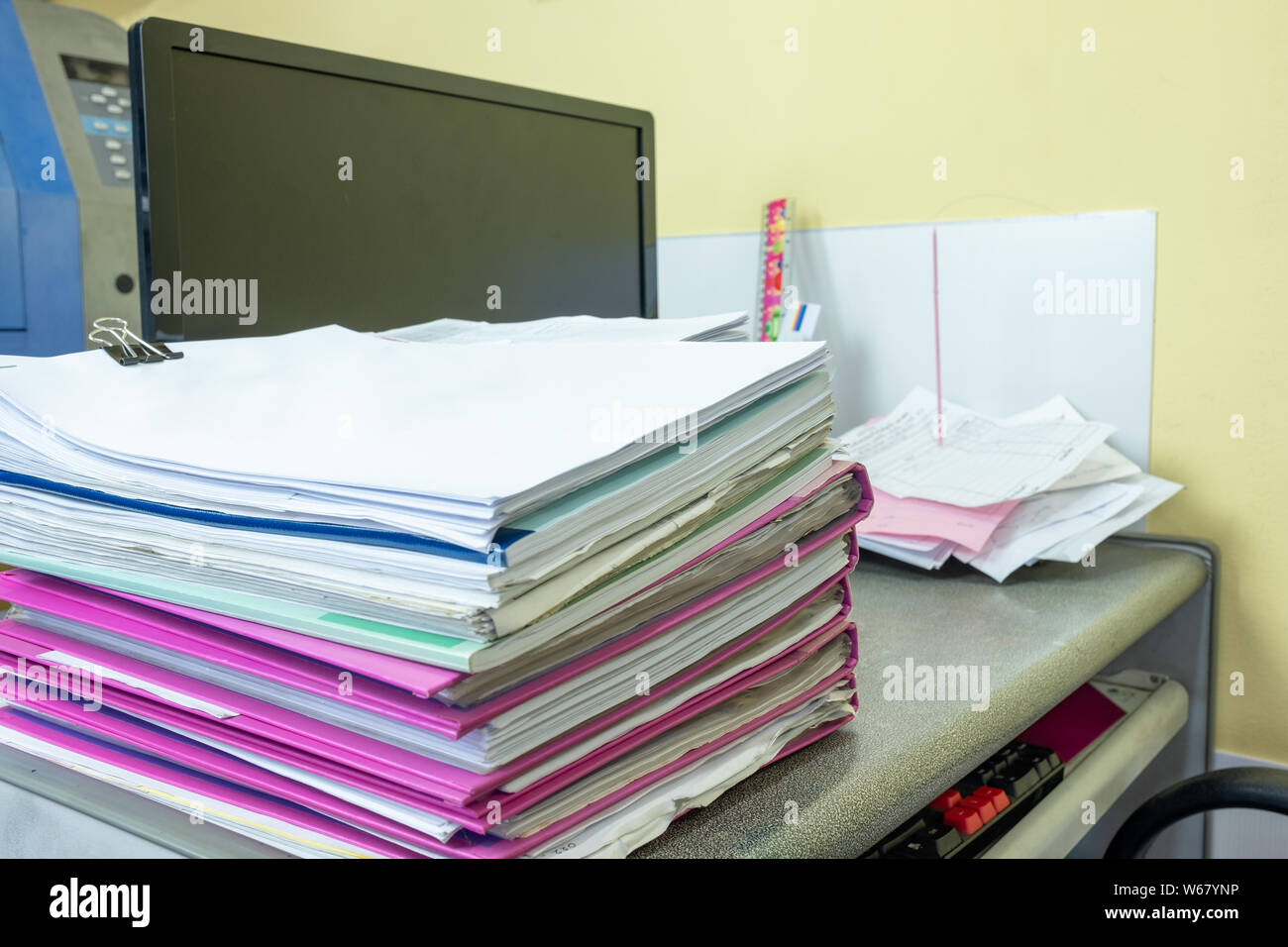 Stack of accounting documents with computer screen on desk in office Stock Photo