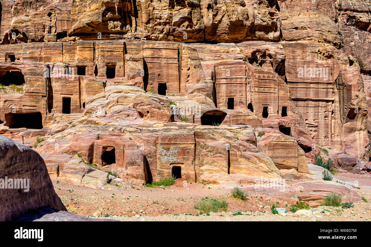 Street of Facades is a row of monumental Nabataean tombs  carved in the southern cliff face that lies past the Treasury and adjacent  to the outer Siq Stock Photo