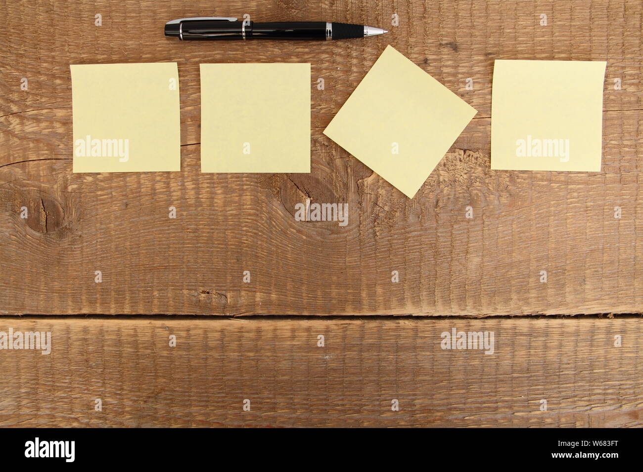 four yellow notes on a wooden table Stock Photo